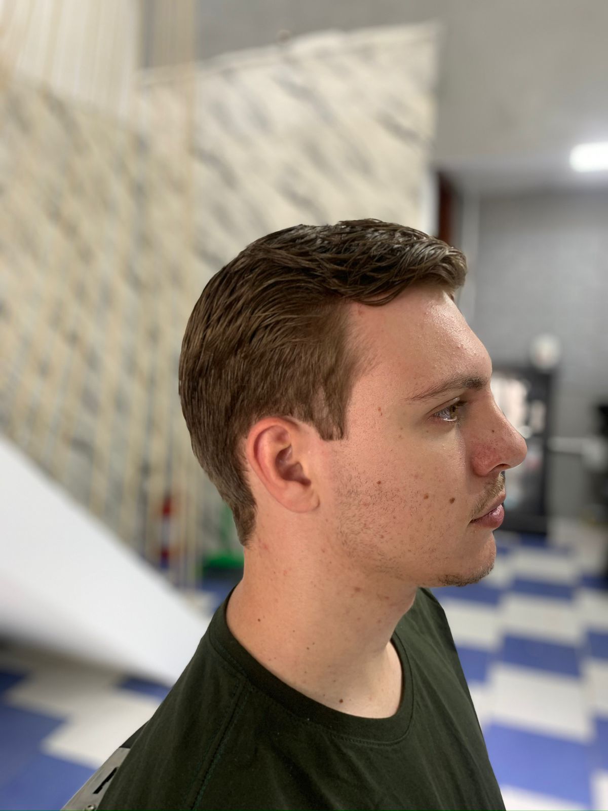 Cliente com corte finalizado na Havana Barbearia, piso xadrez azul e branco ao fundo